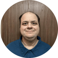 photo of a man wearing a navy blue polo shirt and standing in front of a panelled wall